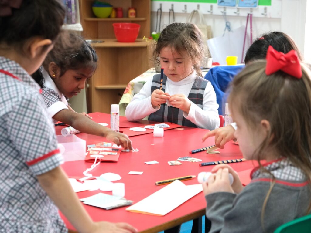 reception students cutting and sticking