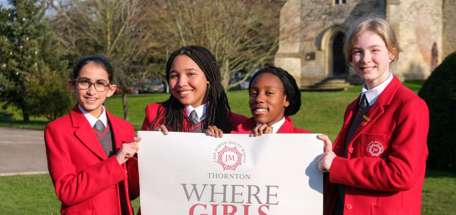 students holding a where girls thrive sign