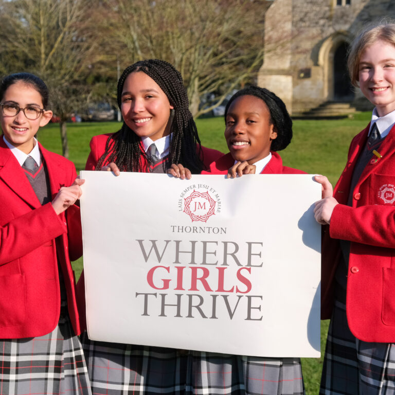 students holding a where girls thrive sign